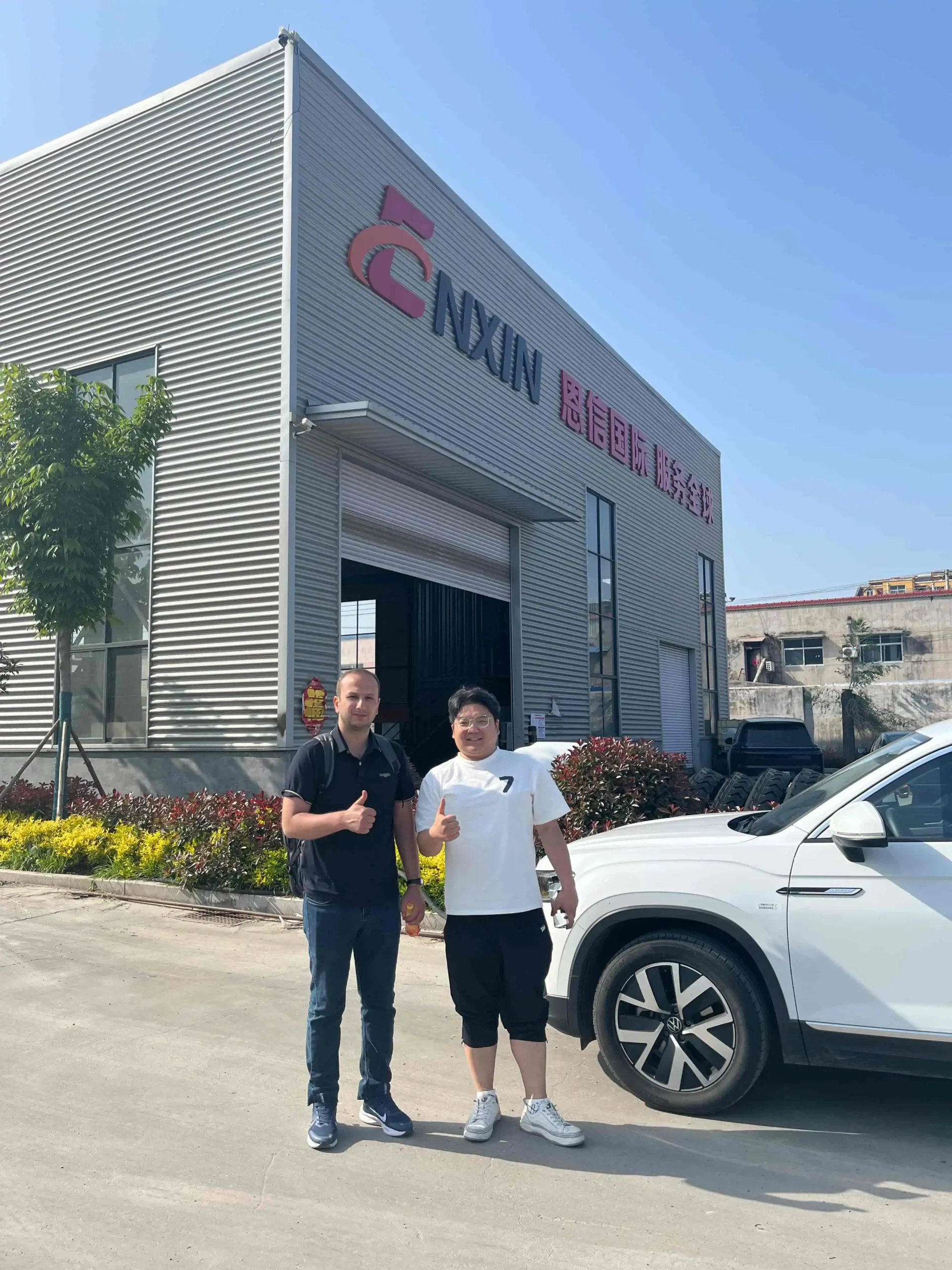 Central Asian customer thumbs up with Enxin manager in front of factory