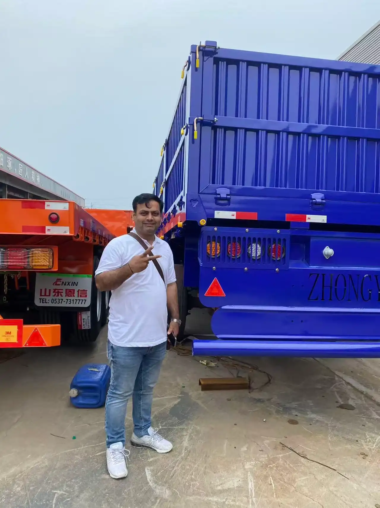 Omani customer thumbs up with Enxin manager in front of premium fence semi trailer