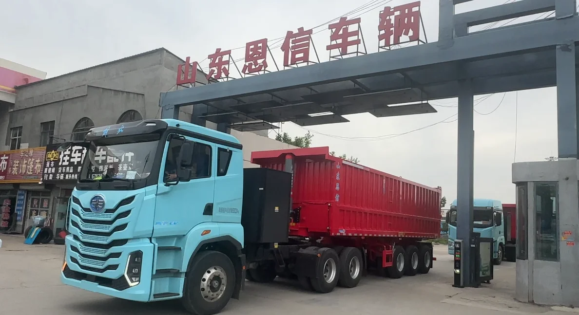 A fleet of brand new red Enxin rear dump tipper trailers driving through the factory gate for port delivery