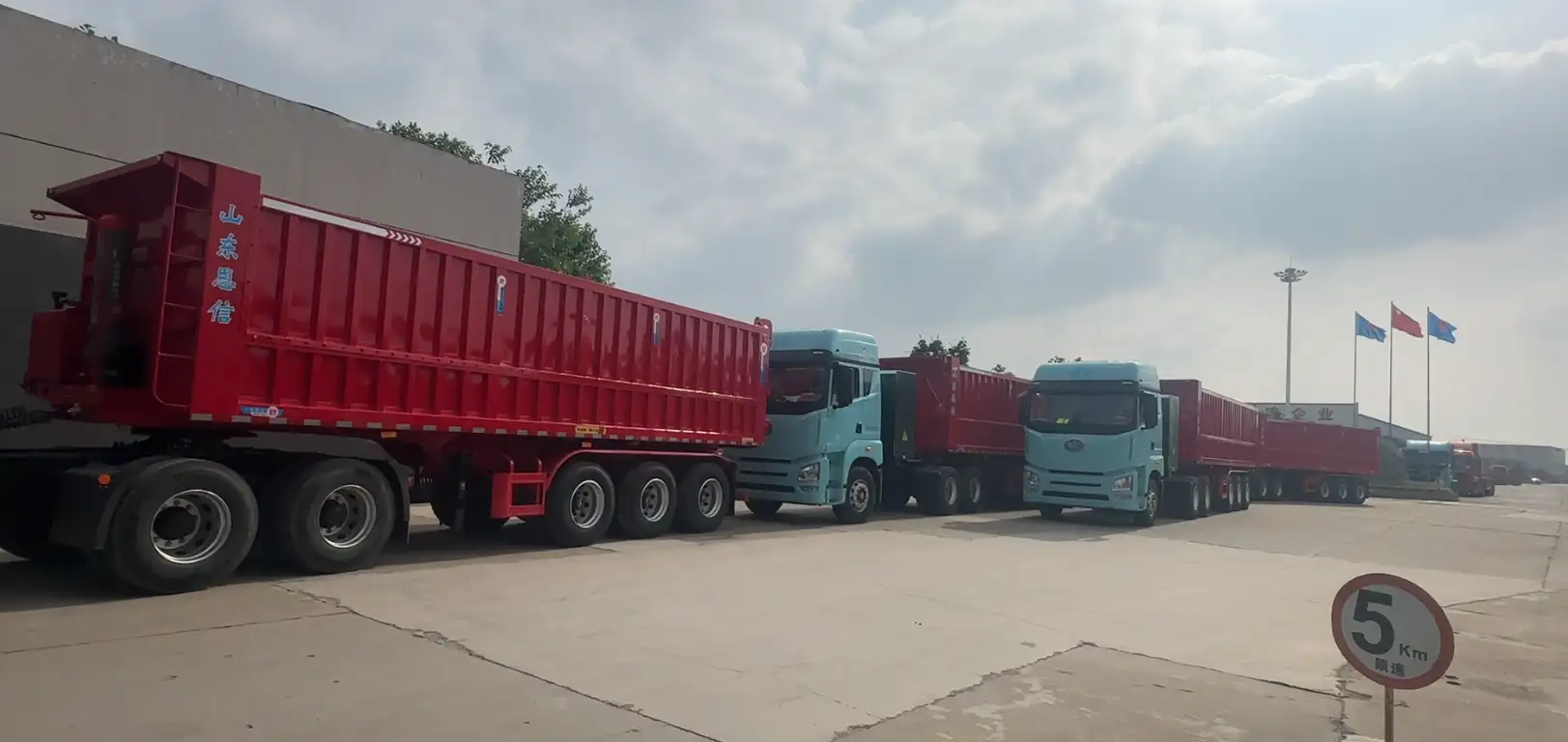 A fleet of brand new red Enxin rear dump tipper trailers lined up at the factory gate for port delivery