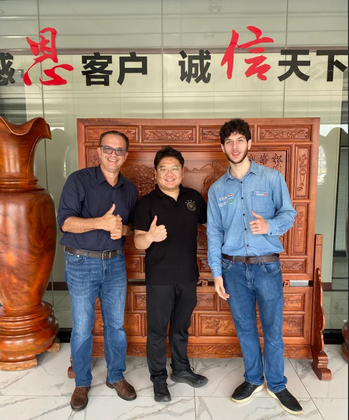 ENXIN management with the visiting overseas client in the company lobby. The calligraphy behind reads "Gratitude to Clients, Integrity Across the World."